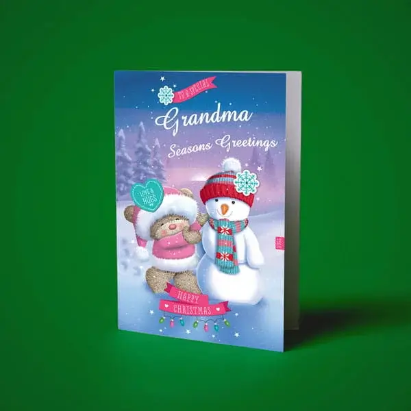 Christmas card for Grandma featuring a snowman and teddy bear in a snowy winter scene with festive seasonal greetings.